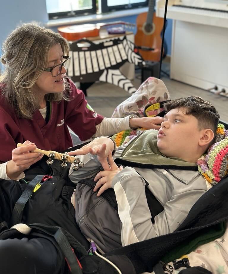 Therapeutic Playworker Karen plays with bells with Mason during a sensory story